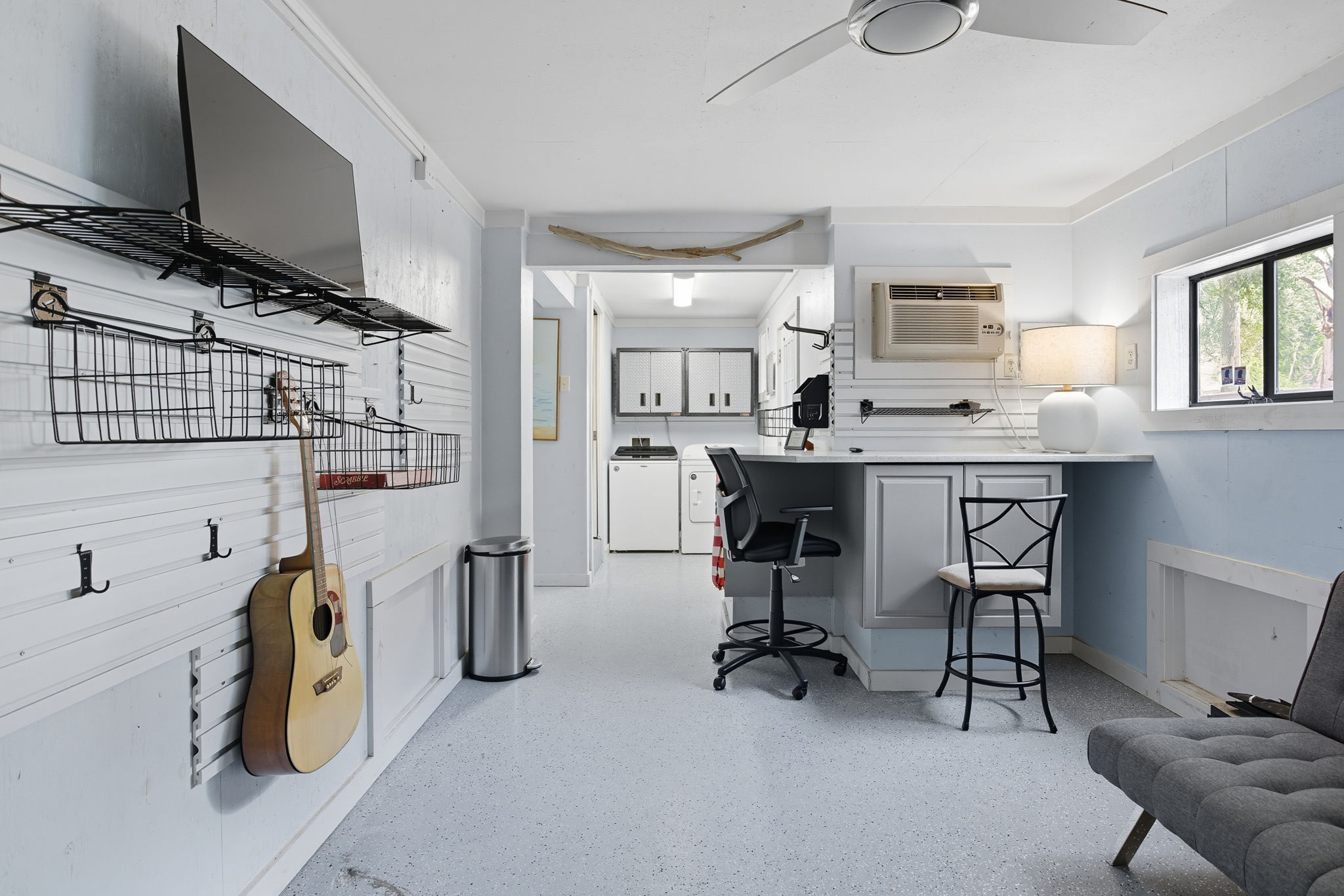 A Man Cave underneath the house has a workstation, seating and room for tools.