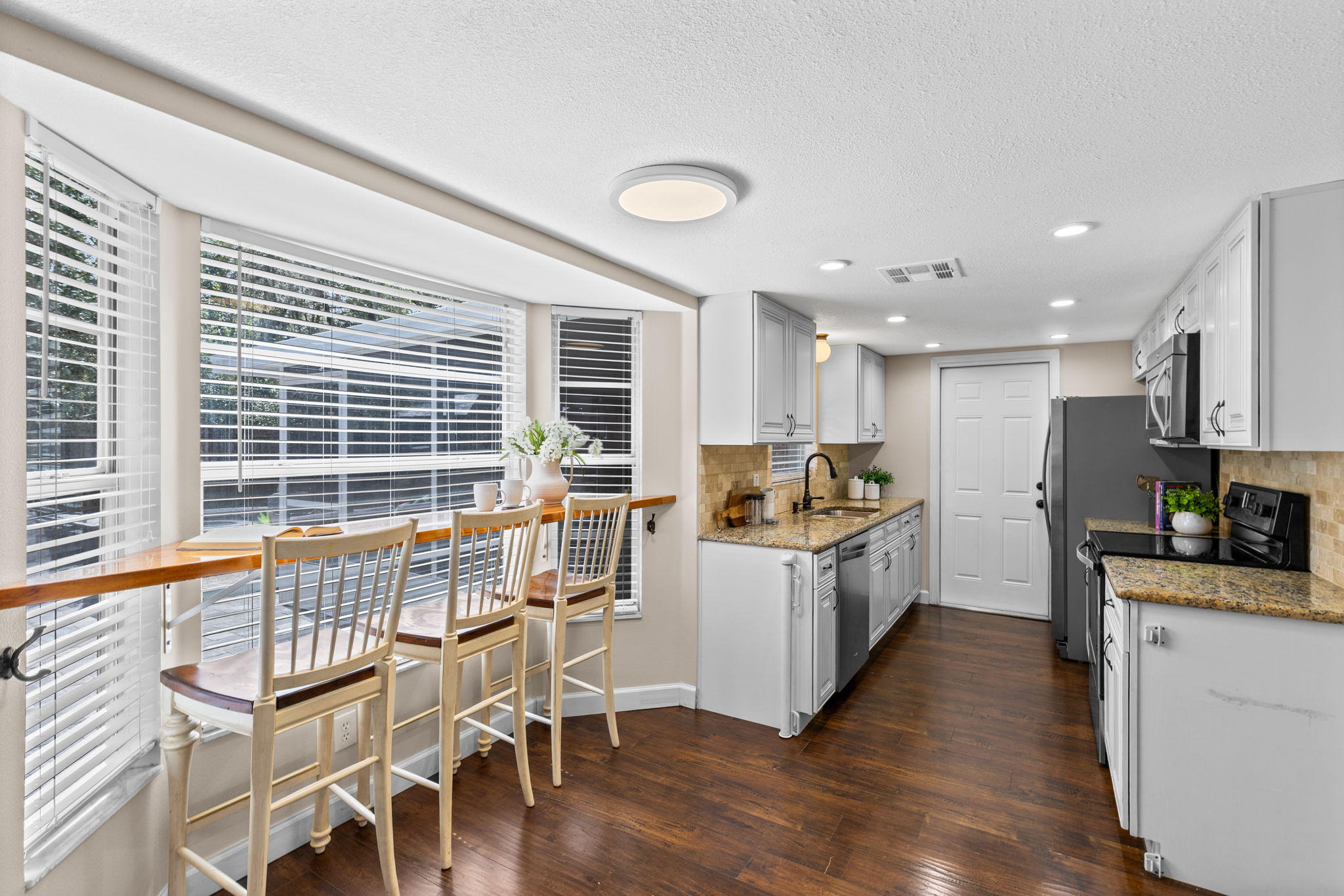 Bay window breakfast nook with built-in bar counter and seating overlooking the backyard.