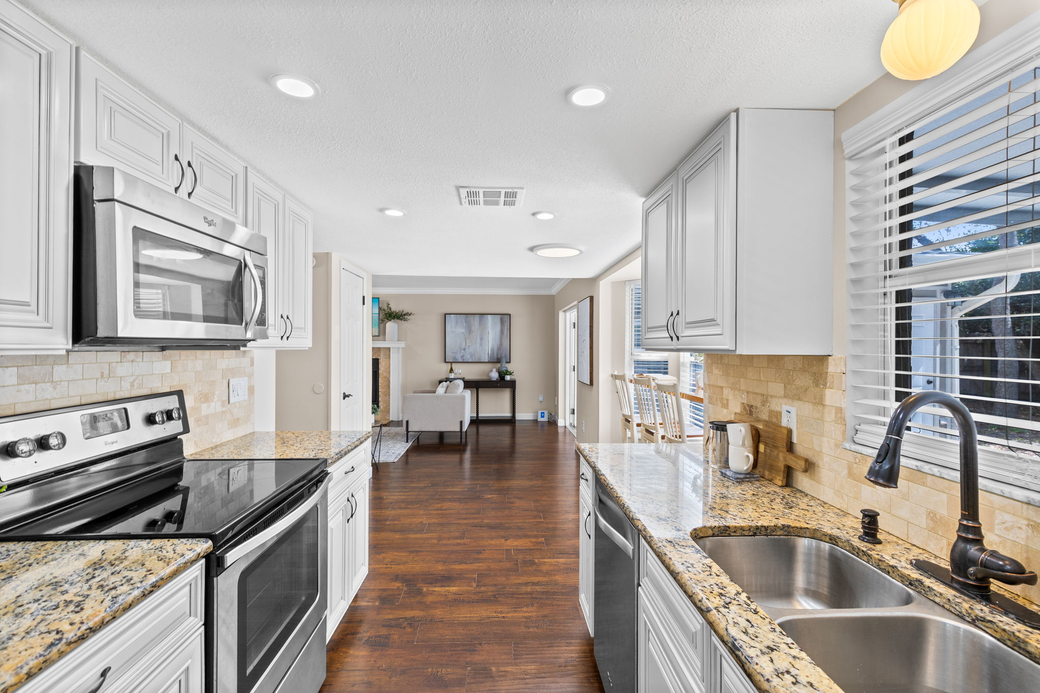 Updated kitchen with granite countertops, raised-panel cabinetry, stone backsplash, and stainless steel appliances.
