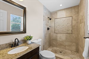 Primary bathroom with granite vanity, rectangular sink, and tiled walk-in shower.