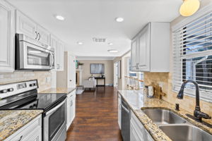 Updated kitchen with granite countertops, raised-panel cabinetry, stone backsplash, and stainless steel appliances.