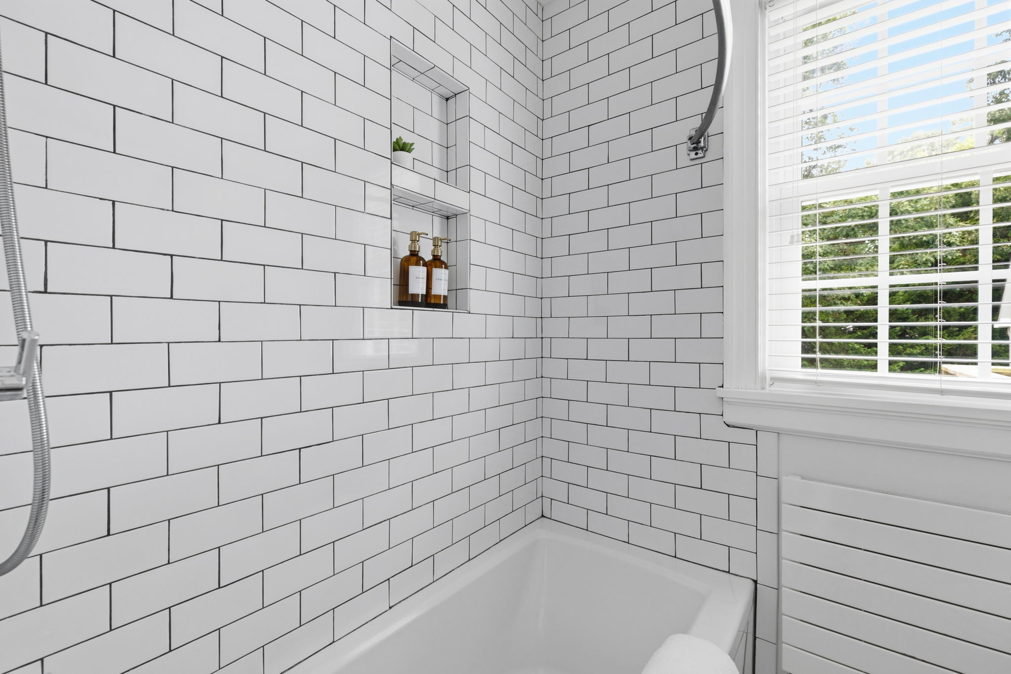 White subway tile surround, built-in shower niche, and a white tall soaking Kohler tub round out this beautiful bath renovation.
