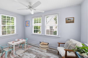 Florida room with bead board ceiling, ceiling fan, LVP flooring & tons of windows make a perfect spot for a reading area, office, or children's play area.