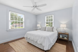 Large front first floor primary bedroom has tons of natural light, hardwood floors, high gloss paint, and ceiling fan.