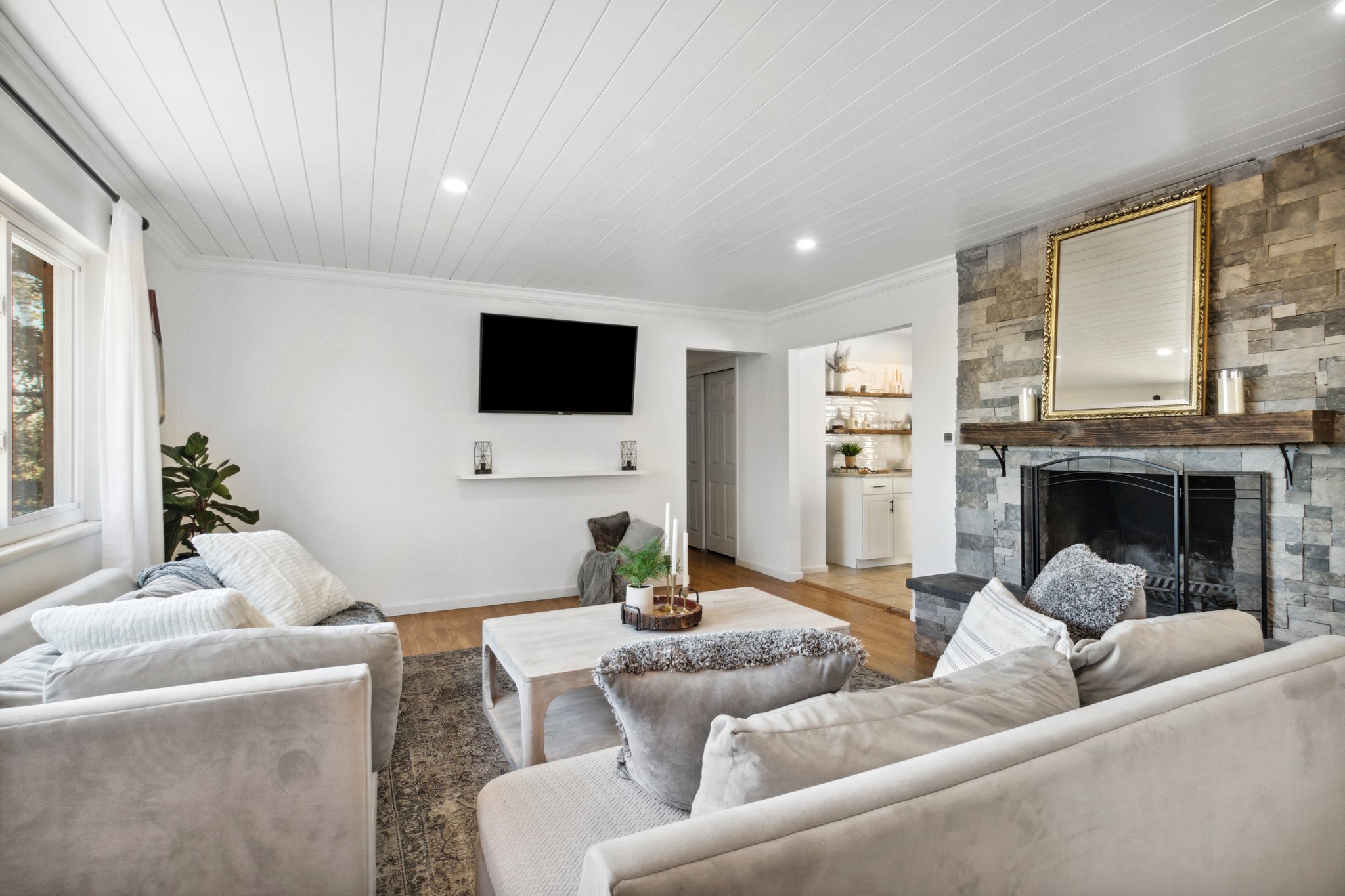 Living Room on Main Floor with Shiplap Ceiling and Stacked Stone Fireplace