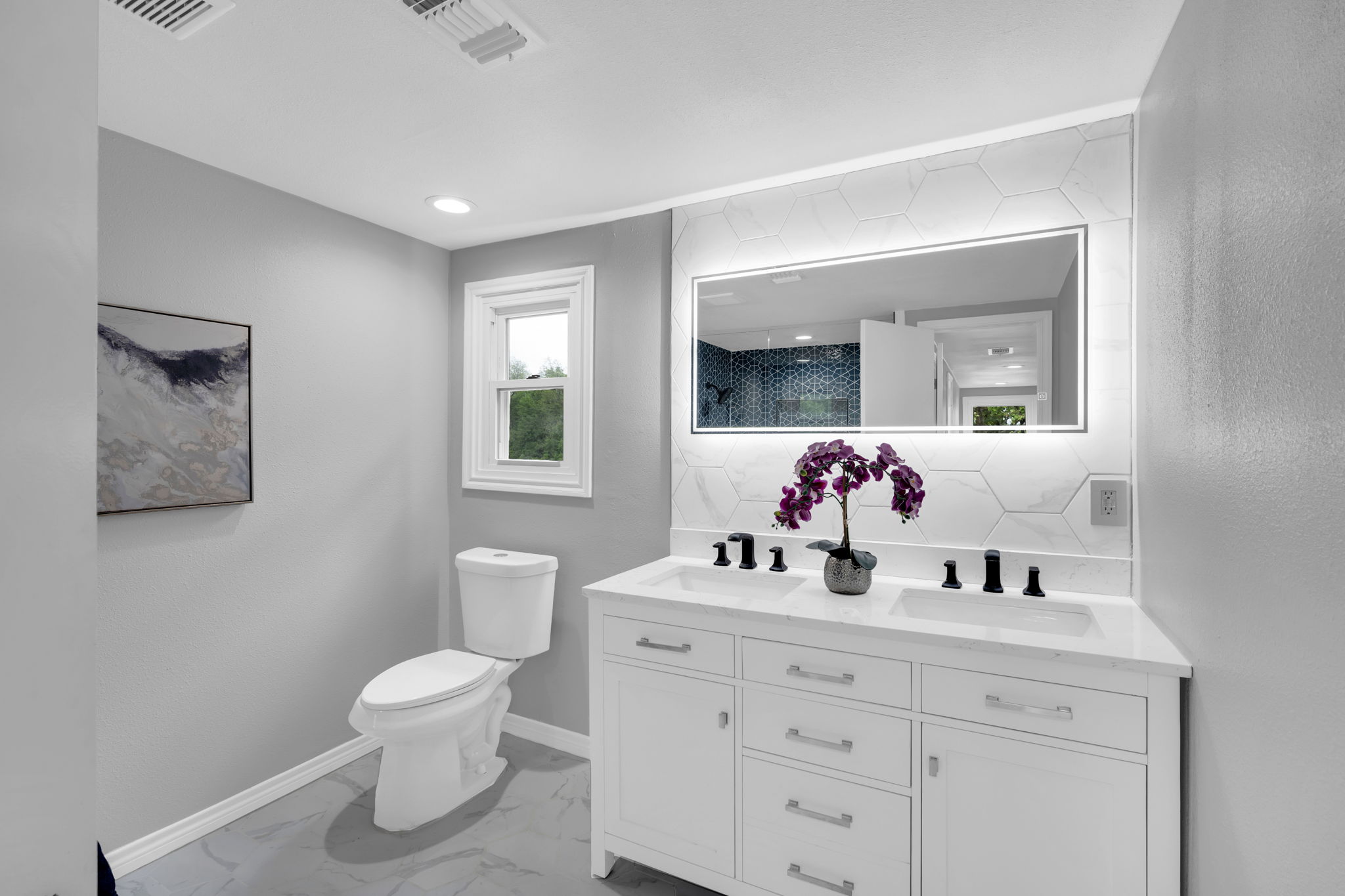 Updated bathroom with lit mirror and tasteful backsplash above your dual vanity