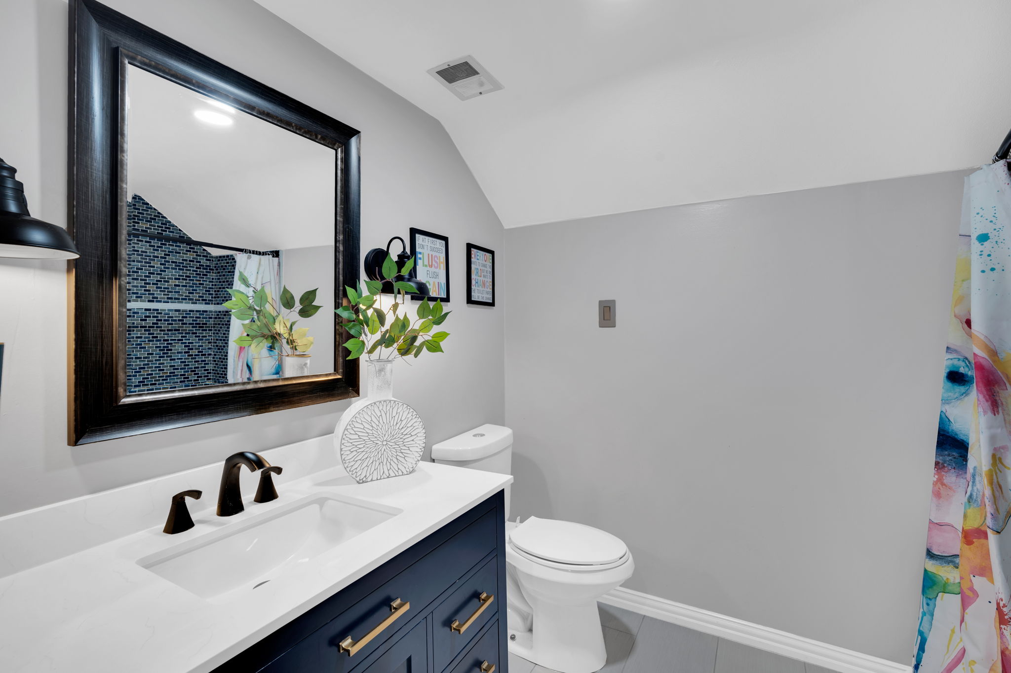 Bathroom provides large vanity, toilet, tile flooring, and lofted ceiling