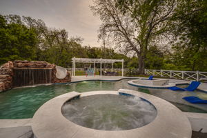 Come on in! View of pool features a patio with pergola and customized water feature