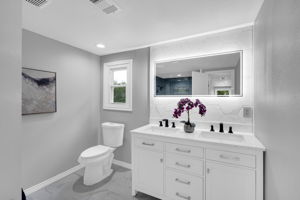Updated bathroom with lit mirror and tasteful backsplash above your dual vanity