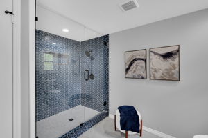 Modest bathroom features an oversized tile shower and neutral tile flooring