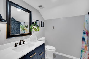 Bathroom provides large vanity, toilet, tile flooring, and lofted ceiling