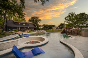Uniquely designed pool and spa with water feature including a fire pit, slide and waterfall