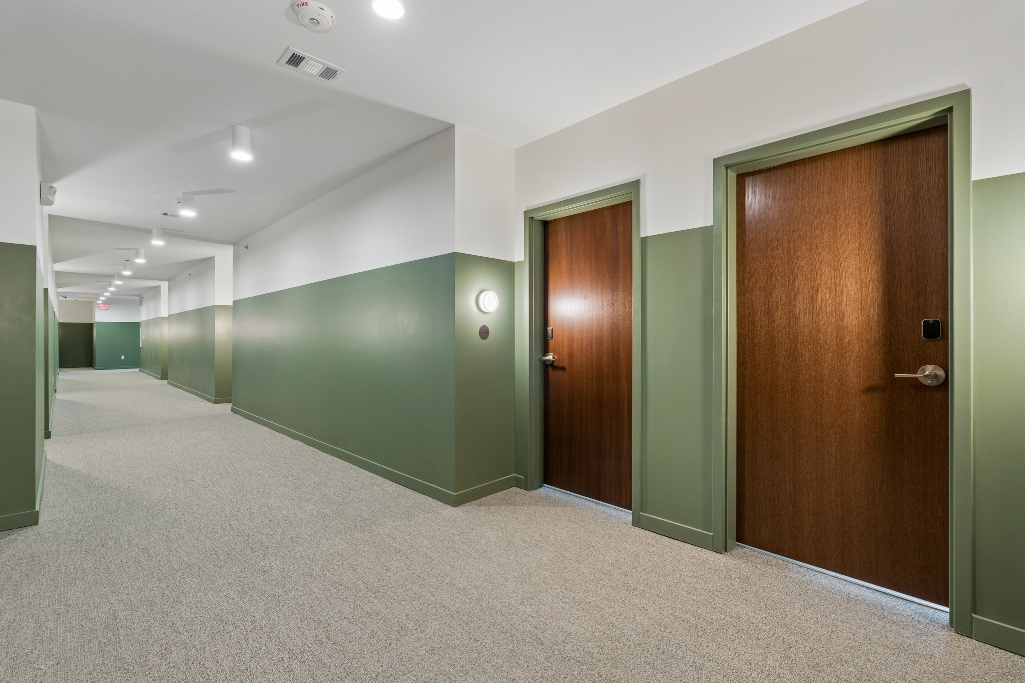 Resident corridor with sage green walls and wood unit doors