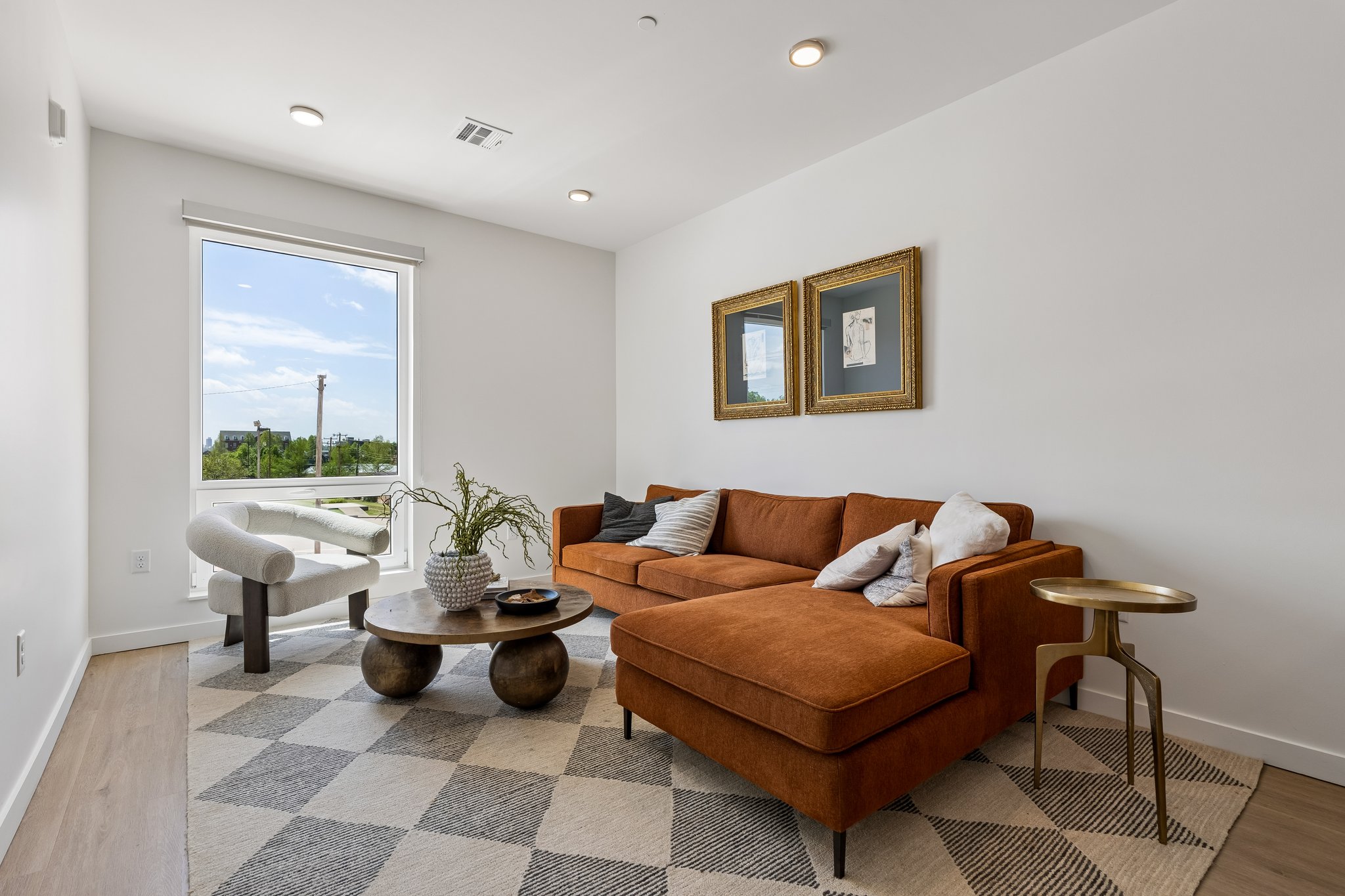 Staged model unit living room with a rust sectional and framed art