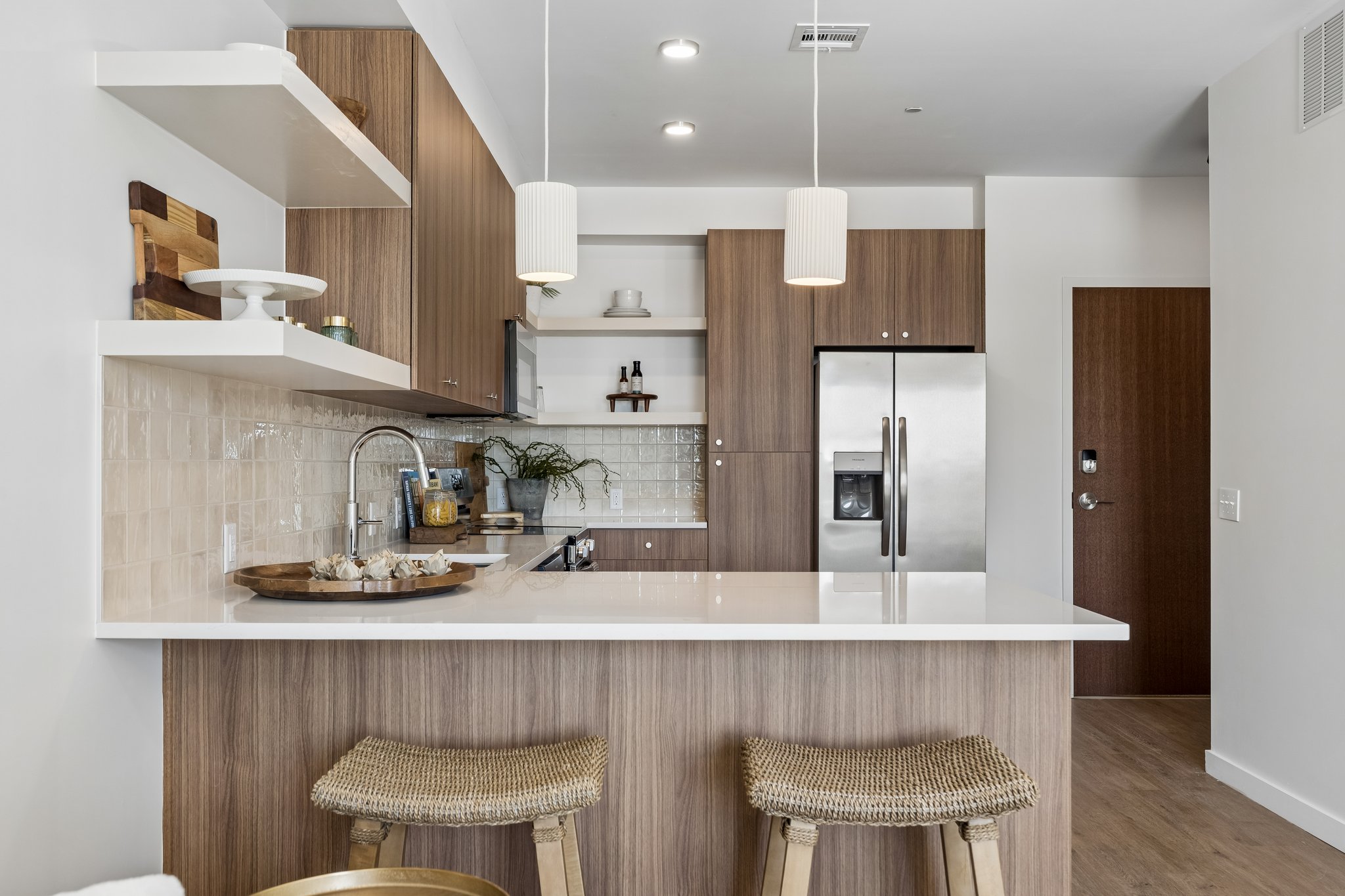 Model unit kitchen island with pendant lights and two counter stools