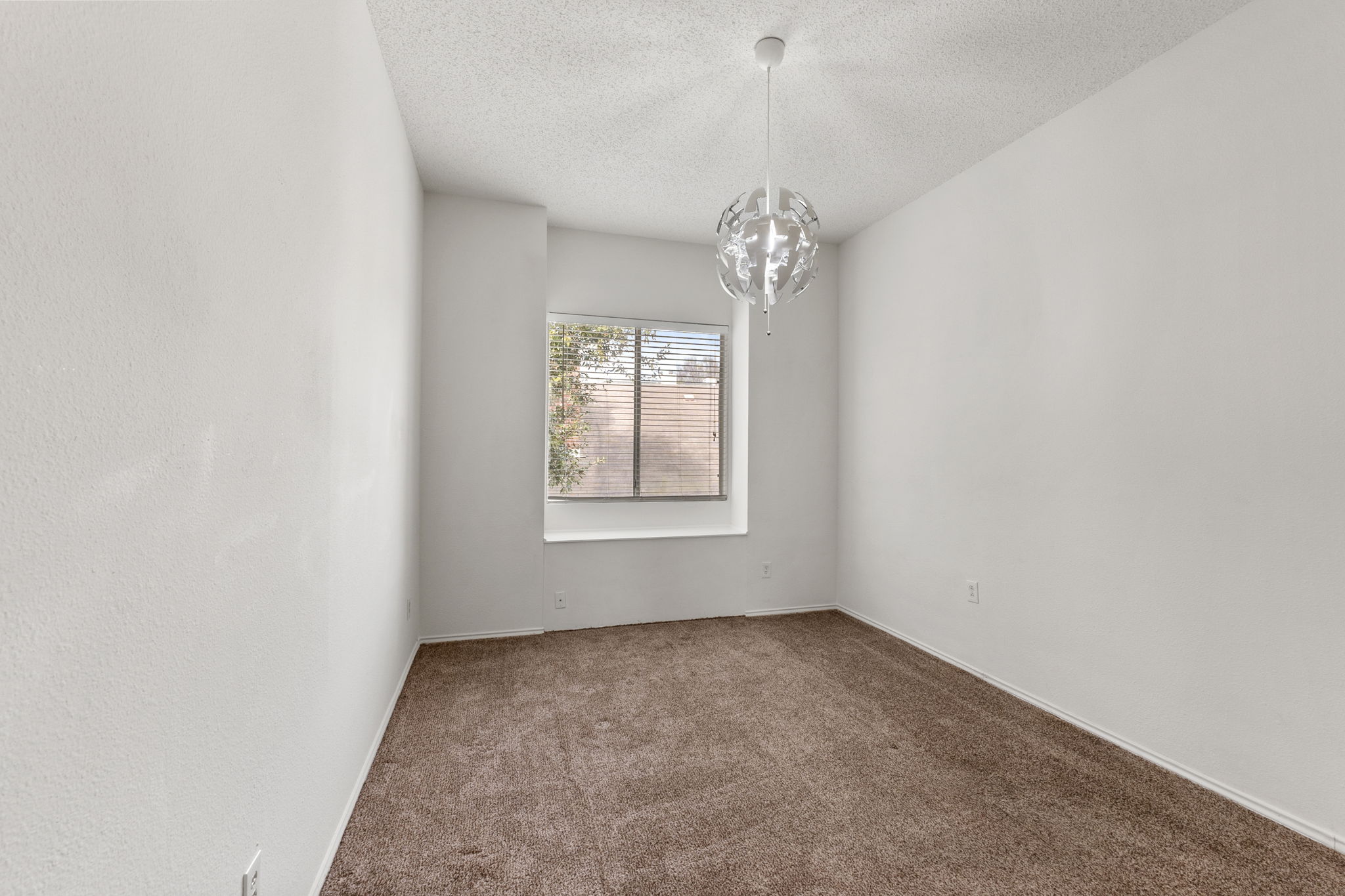 Neutral brown carpet and off white walls are features of this third bedroom.