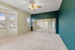 The primary bedroom features a beautiful bay window that fills the room with natural light. The sliding glass doors provide access to the closet. The complement the deep, rich forest green walls, create a serene and inviting atmosphere.