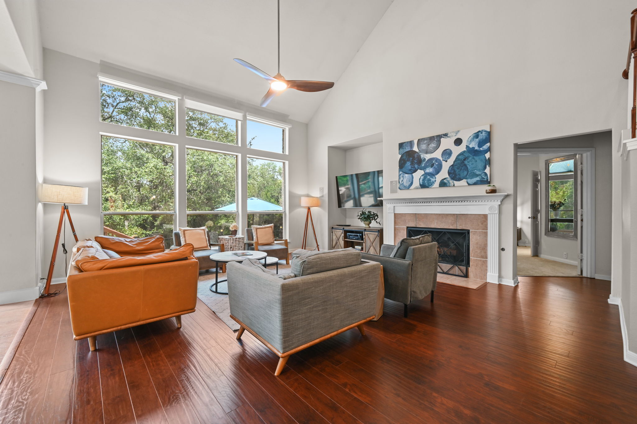 The great room is nothing short of spectacular — 12-foot floor to ceiling windows frame a magnificent canopy of mature live oaks and a sweeping view of the woods.