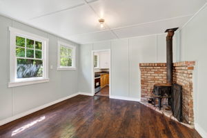 The den with a centrally located wood burning stove.  The kitchen is in the background.