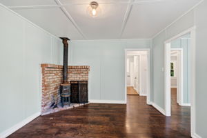 The den with a centrally located wood burning stove.  The living room is to the right and the bedrooms and bathroom forward.