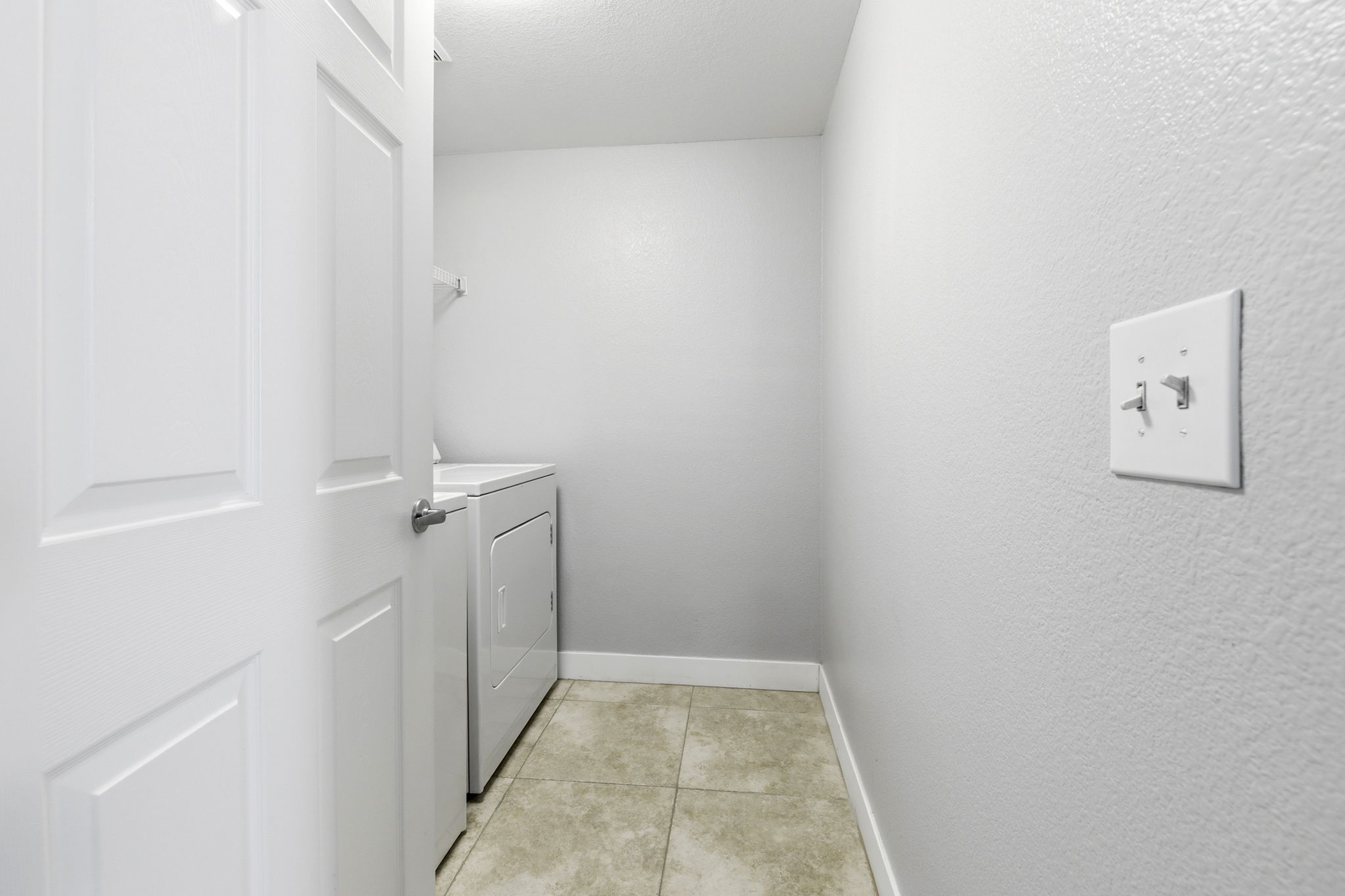 Entry to laundry room with tiled floor.
