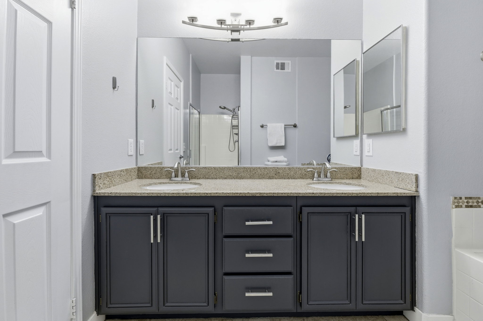 Dual sinks in primary bathroom with custom lighting.