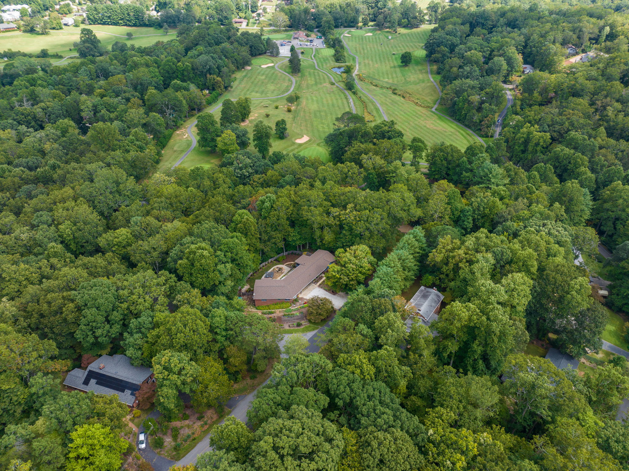Property Surrounded by Woods and scatered Neighbors with Golf Course in Background View