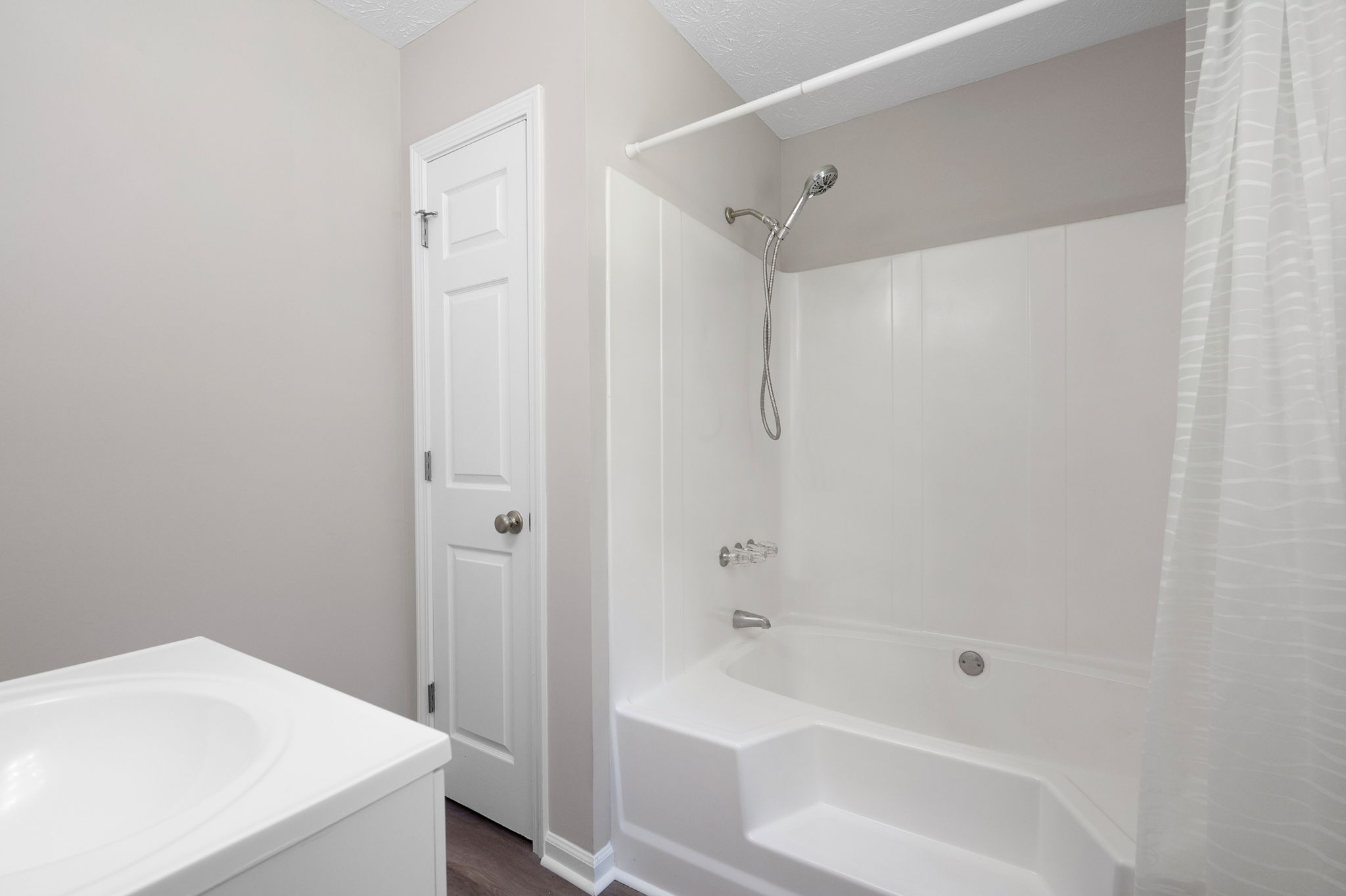 The newly renovated a primary bathroom features new flooring, a newly glazed bathtub...