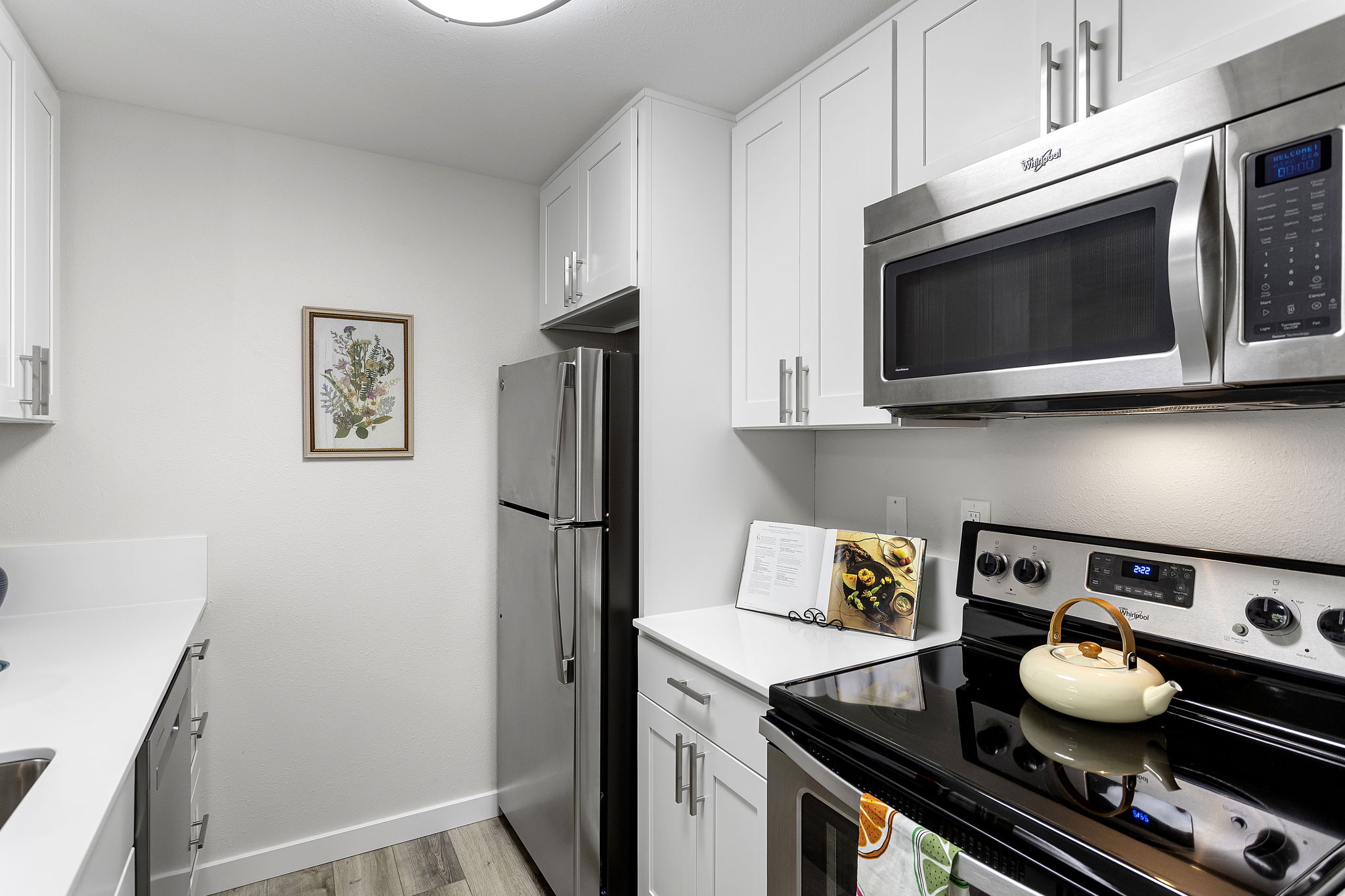 Unused since renovation, the kitchen pairs new white shaker cabinetry and quartz counters with a new stainless microwave and dishwasher.