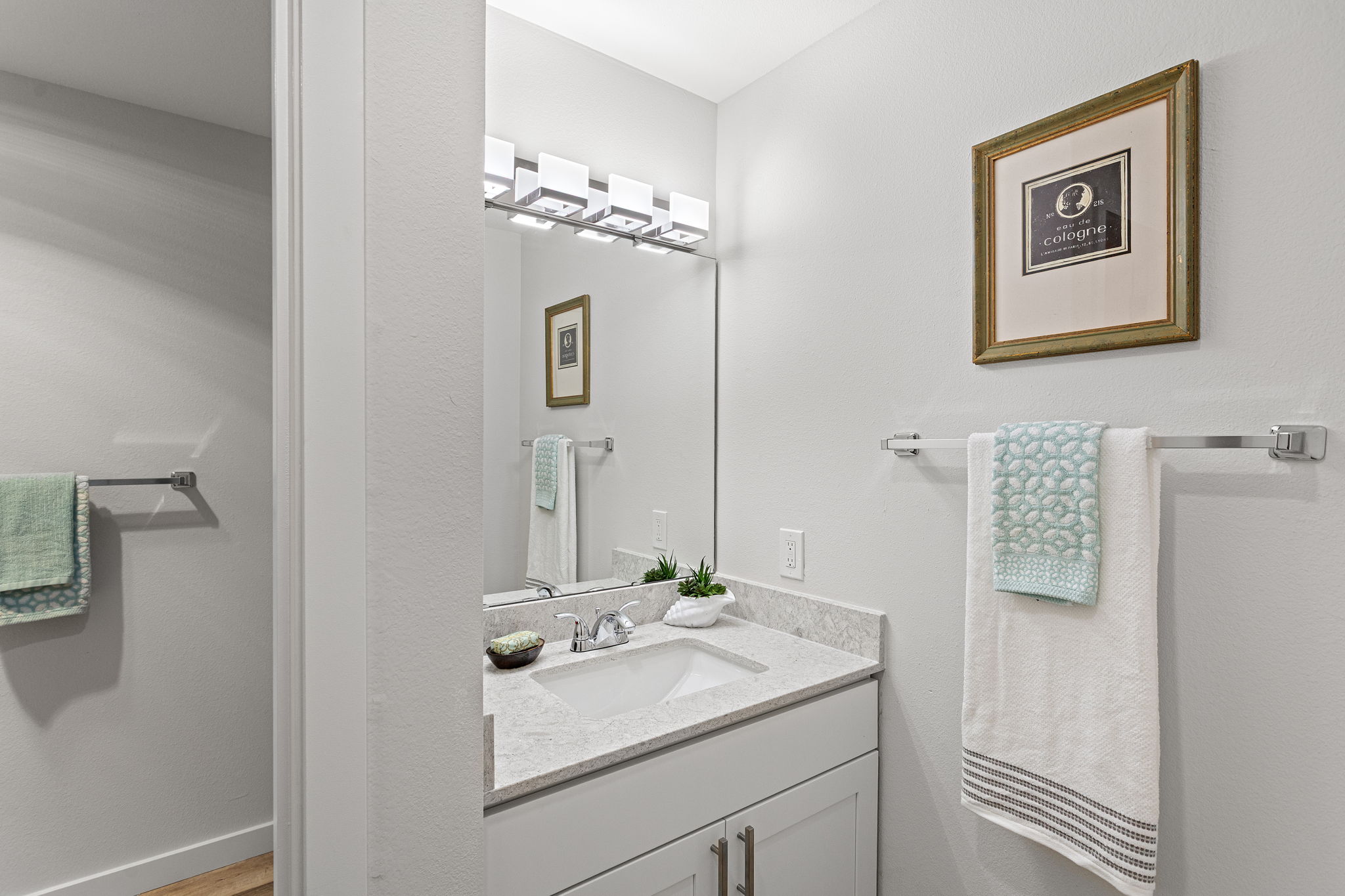 The separate dressing area adds a second getting-ready zone, finished with a sleek new undermount sink, quartz counter, faucet, and lighting. The toilet and bath are through the door on the left.