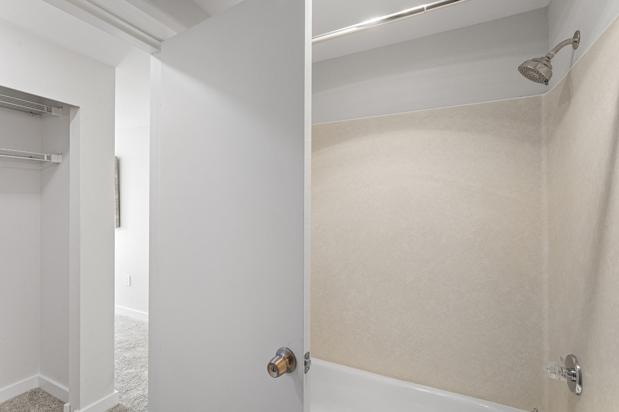 This angle does double duty: it shows the original tub and surround, while the sightline back into the primary bedroom helps make sense of the suite’s separate bath and dressing/closet area.