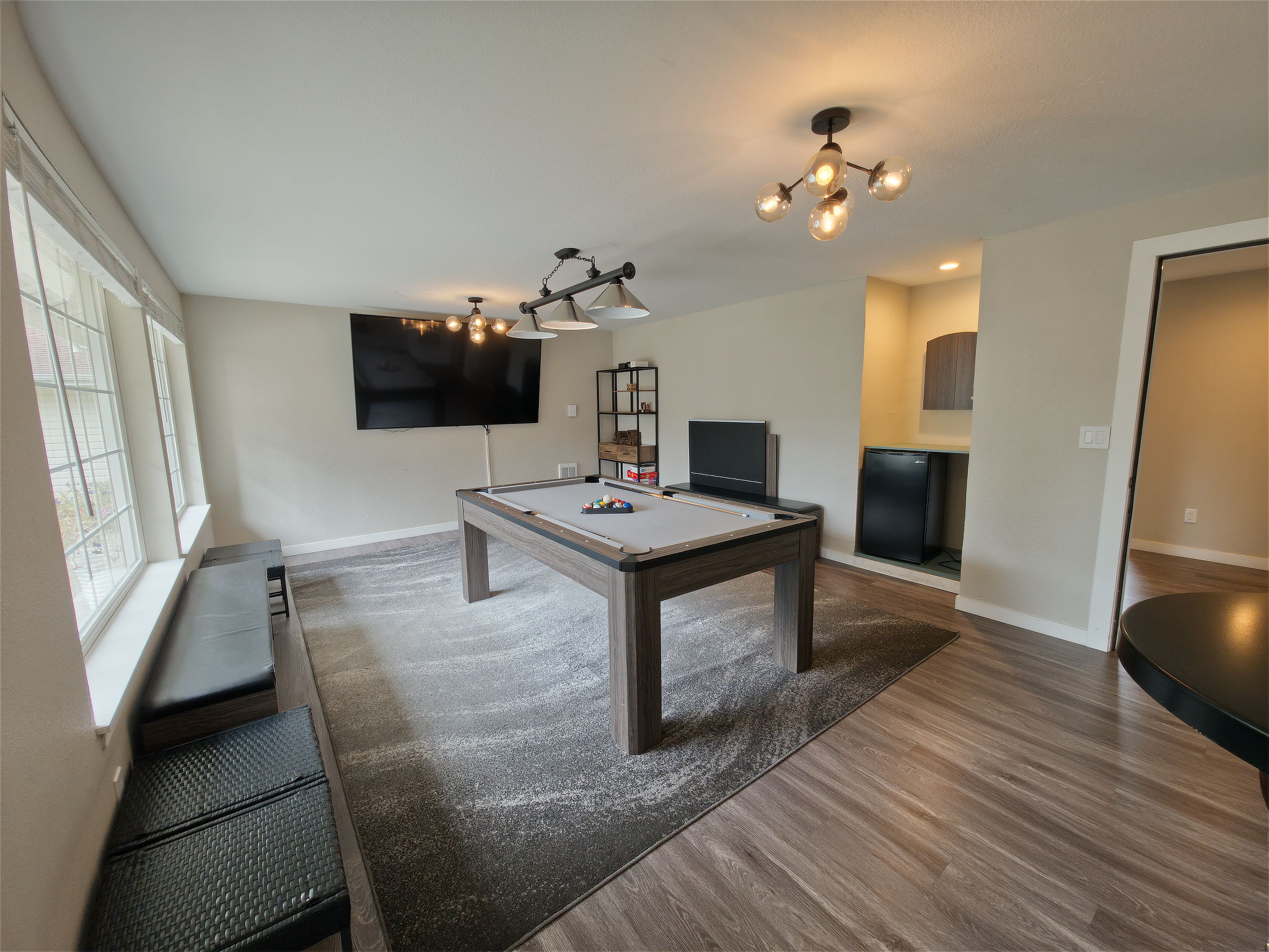 A wall of windows keeps the game room bright, and the mini fridge keeps cold drinks close without leaving the room.