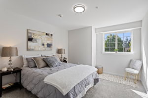 A sunny window bump-out creates a natural sitting or reading nook in the generous primary suite, with west-facing afternoon light, a separate dressing/closet zone with new vanity and lighting, and a private bath.
