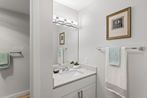 The separate dressing area adds a second getting-ready zone, finished with a sleek new undermount sink, quartz counter, faucet, and lighting. The toilet and bath are through the door on the left.