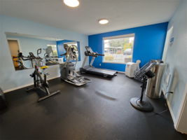 The clubhouse fitness center includes cardio and strength equipment, free weights, and a portable air conditioner for added comfort.