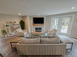 The clubhouse living area centers on a fireplace, with comfortable seating and direct access to the outdoor gathering space.