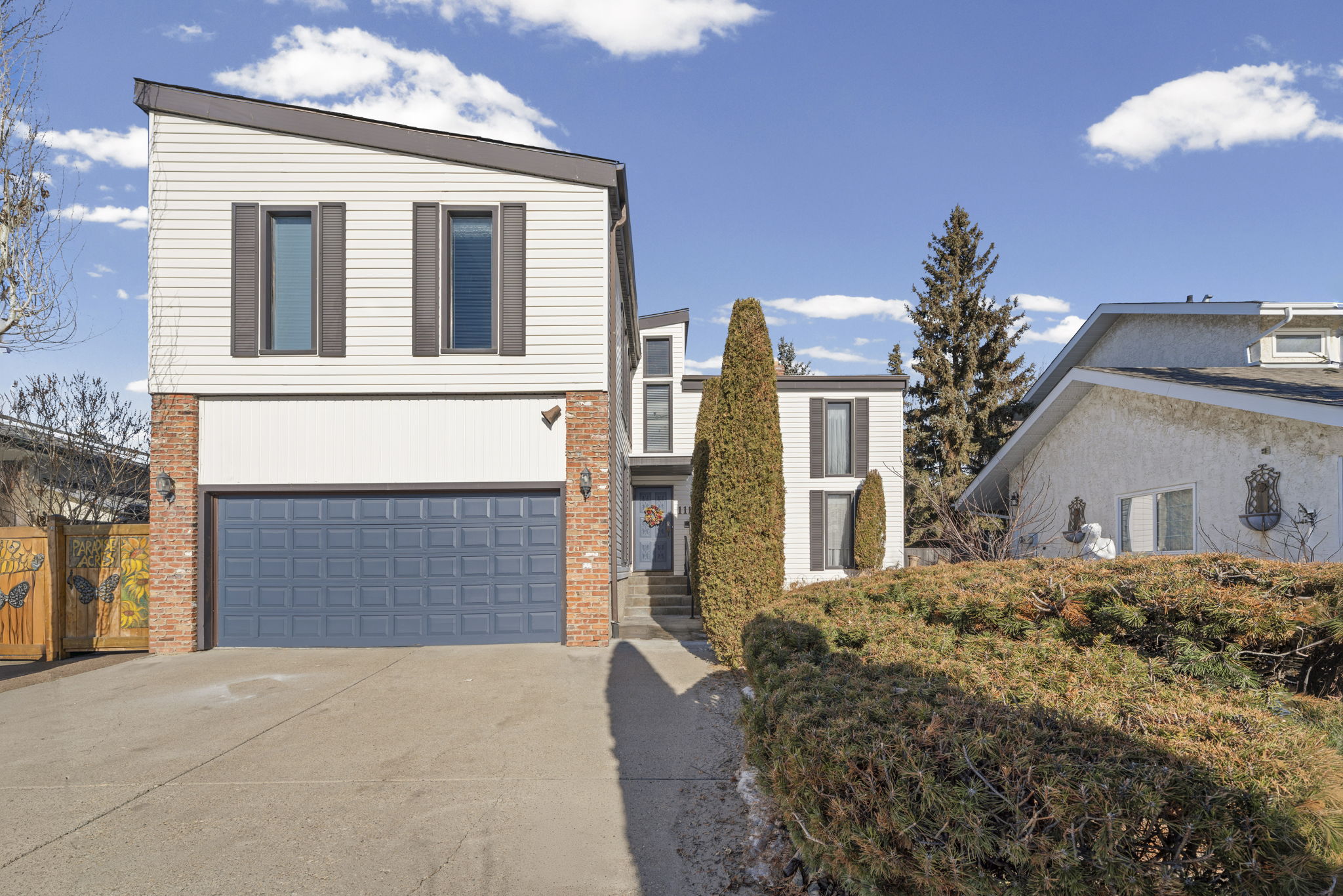 Front elevation of the home with grey siding, brick trim and a blue garage door.
