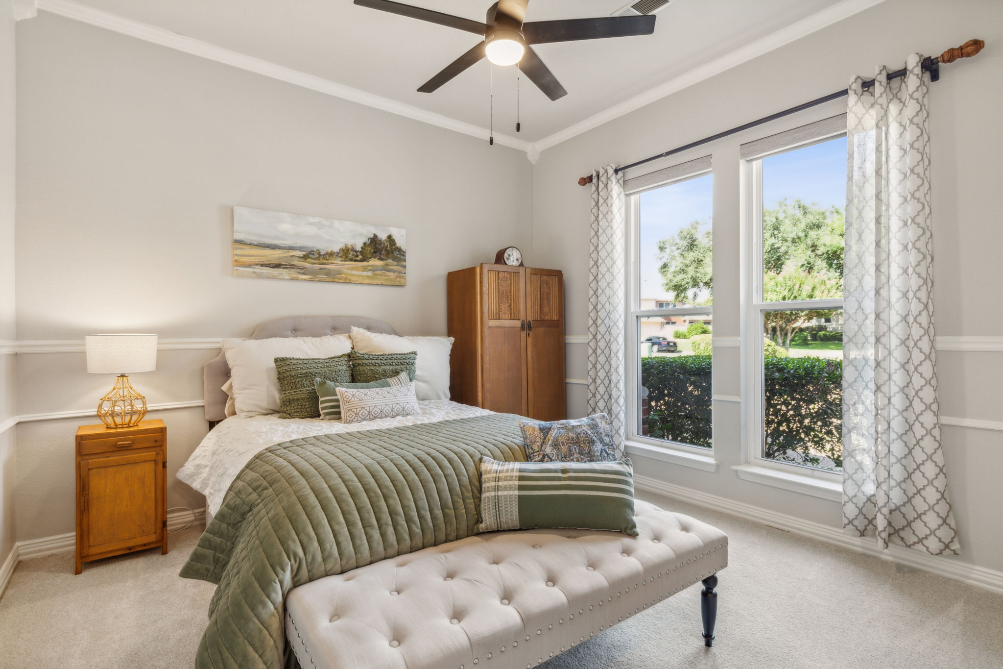 The first-floor guest bedroom offers a spacious walk-in closet and a charming view of the expansive lot. Enhanced with an upgraded ceiling fan, crown molding, and chair railing, this room showcases the home's elegance and ensures a pampered experience for your guests.