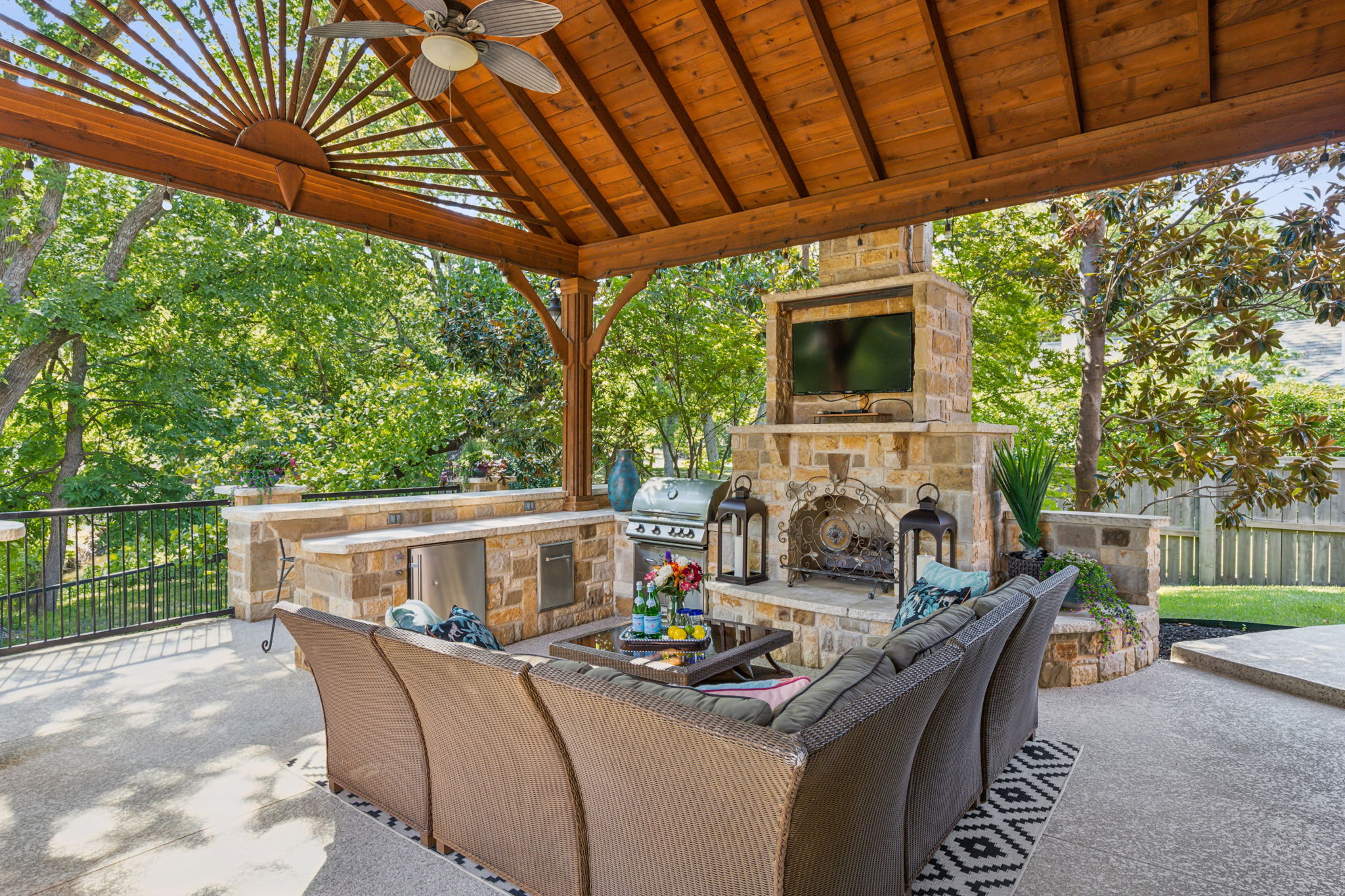 The outdoor living area is equipped with a bar, fireplace, TV, refrigerator, gas grill, and built-in trash can. BONUS: The TV will remain with the home.