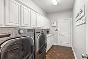 The utility room features a sink, cabinetry, and ample counter space for folding and organizing laundry.