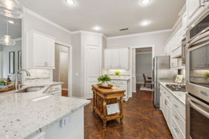 The kitchen includes a single-basin sink, under cabinet lighting, pendant lights above the breakfast bar, a walk-in pantry, and an island. NOTE: The refrigerator and kitchen island will remain with the home.