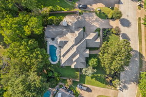 An overhead view of the home showcases the greenbelt, pool, arbor, backyard greenspace, and an extended driveway for additional parking.