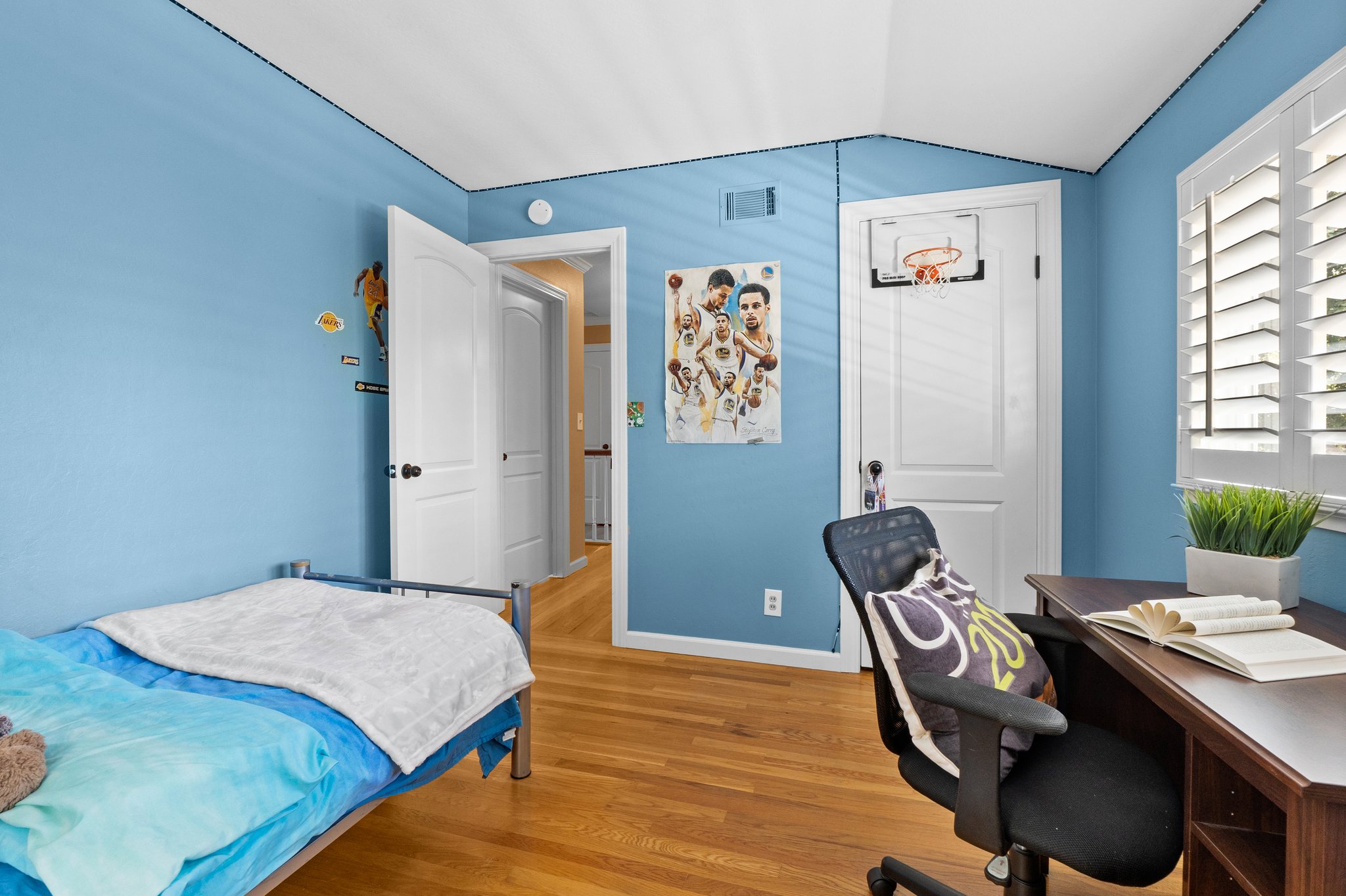 A bedroom furnished with a bed, desk, and a window.