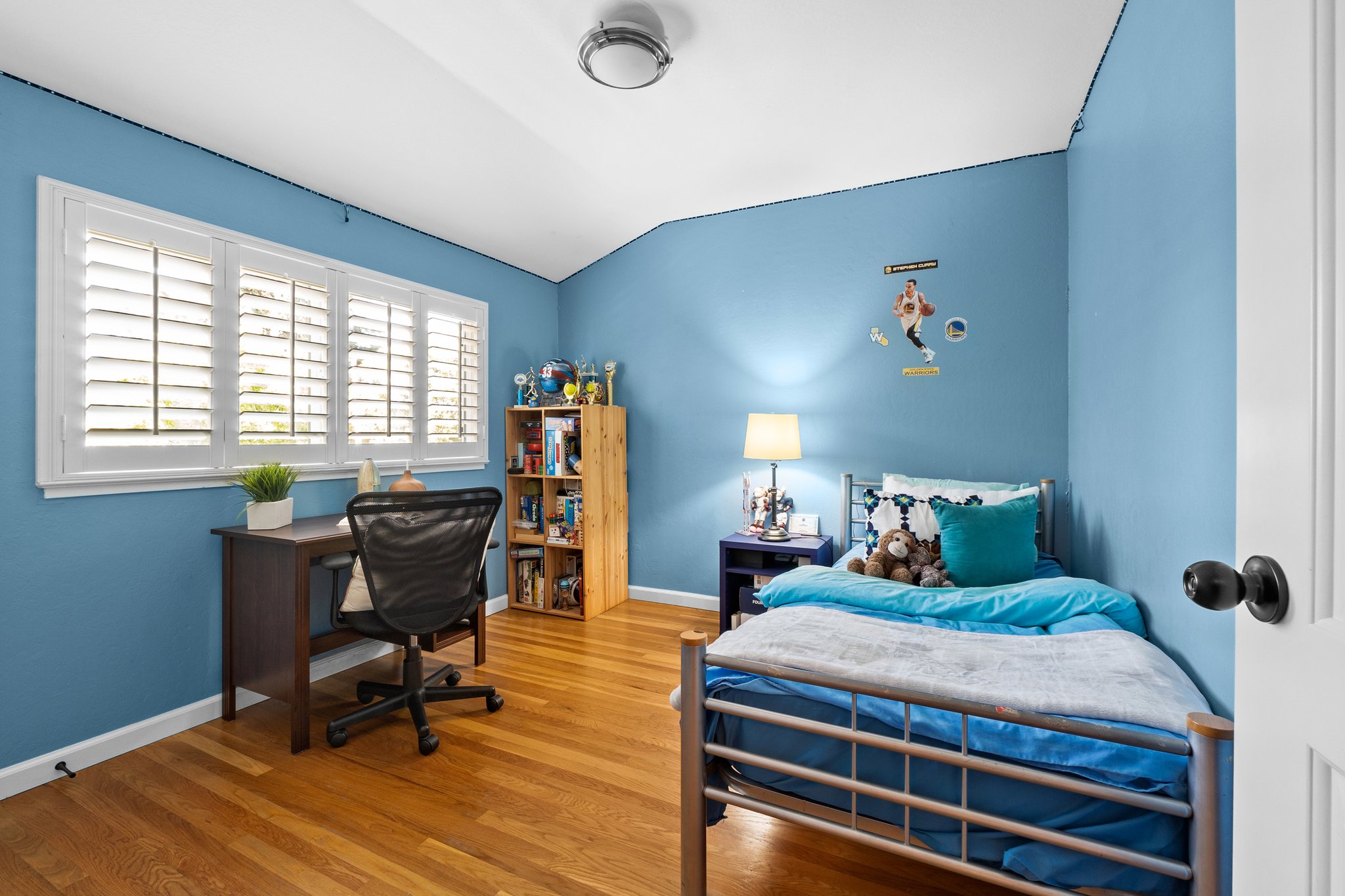 A stylishly arranged bedroom with a cozy bed, work-friendly desk, and ample window.