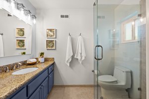 A bathroom designed for the most discerning tastes, showcasing a luxurious sink, an enclosed shower room with glass, and an intricately adorned, full-length mirror.