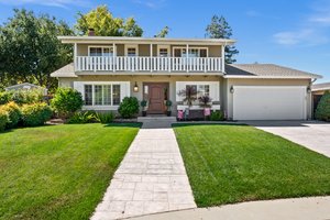 An upscale residence with a spacious, well-tended lawn and a stately, paved driveway.