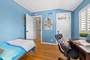 A bedroom furnished with a bed, desk, and a window.