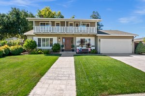 A residence with an expansive lawn and a spacious driveway.