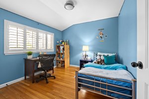 A stylishly arranged bedroom with a cozy bed, work-friendly desk, and ample window.