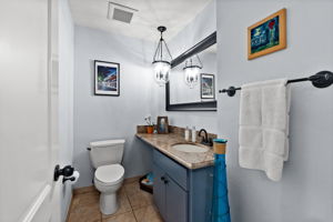 An upscale washroom with a toilet, a decorative basin, and a contemporary mirror.